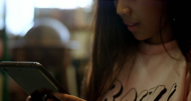 Young woman using smartphone at cafe, focusing on screen with blurred background. Ideal for illustrating concepts of modern communication, social media usage, digital lifestyle, and technology in everyday life. Possible use in advertisements, lifestyle blogs, tech articles, or online content related to youth culture and digital trends.