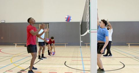 Indoor volleyball team practicing at net spiking passing jumping with diverse male players