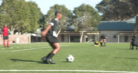 Teenage soccer players practicing drills on sunny field
