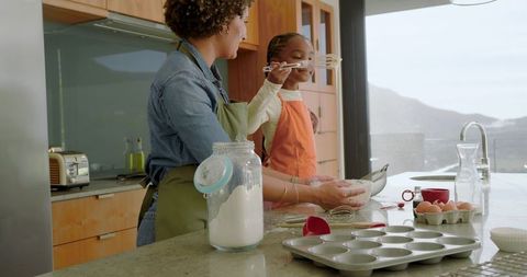Mother and Daughter Baking Together Tasting Batter in Kitchen