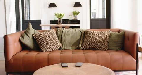 Cognac leather sofa with olive cushions and textured woven pillows in modern living room