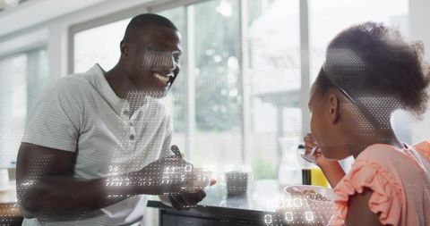 Smiling father sharing breakfast with daughter at bright kitchen counter, family bonding