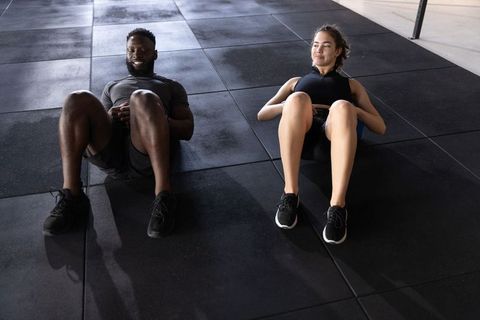 Duo performing synchronized crunches on gym floor building core strength and motivation