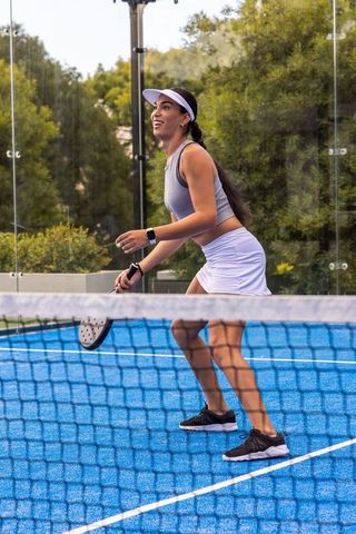 African american woman playing paddle tennis on blue court preparing to volley