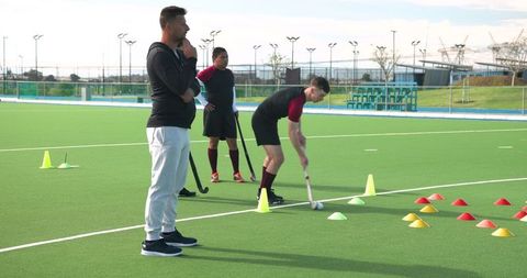 Diverse Team Hockey Practice on Synthetic Turf with Coach Guidance
