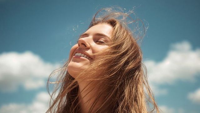 Carefree Woman Enjoying Gentle Breeze Under Clear Skies