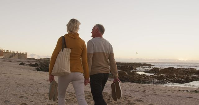 Happy senior caucasian couple walking and holding hands at seaside on sunny day. Summer, senior lifestyle, vacation and activity, unaltered.