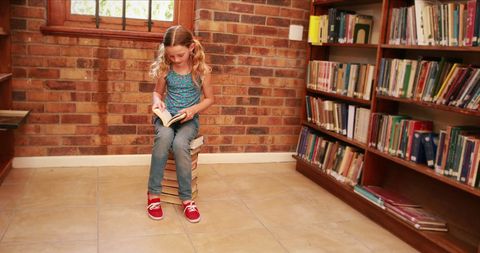 Young Girl Reading on Pile of Books in Library