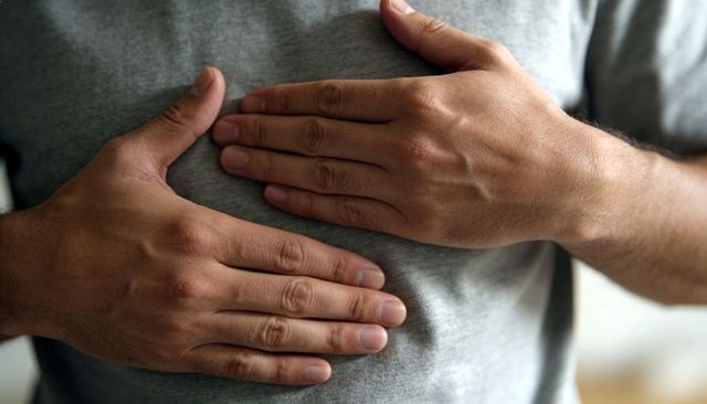 Adult man placing hands on chest showing calm self-care, heart health and chest discomfort