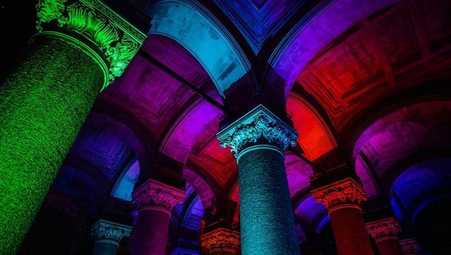Neon-lit corinthian columns and vaulted arches, vibrant basilica interior at night