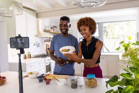 African american couple recording healthy breakfast vlog in bright modern kitchen