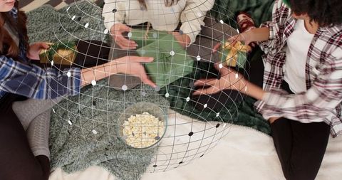 Friends sharing gifts and popcorn on cozy living room floor with virtual wireframe globe