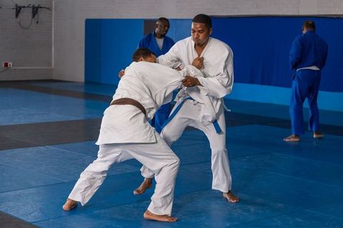 Martial Arts Students Training Judo Techniques on Blue Mats in Dojo
