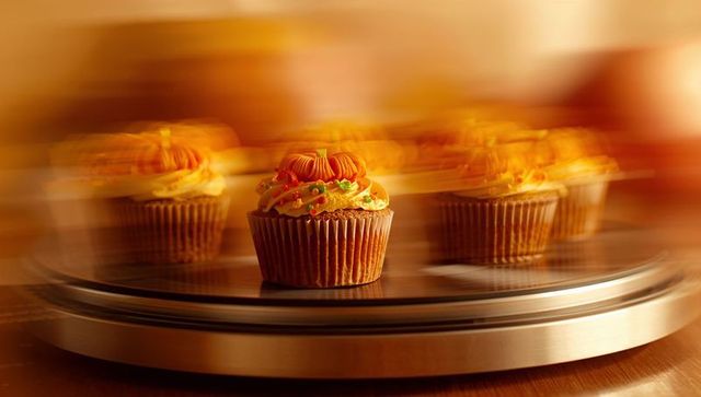 Festive Pumpkin Cupcake on Rotating Cake Stand in Warm Lighting