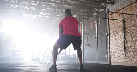 Athletic man engaged in intense battle rope training at gym
