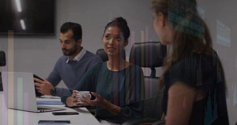 Business team discussing analytics with woman holding mug in modern boardroom