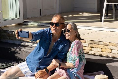 Senior couple taking selfie on sunny terrace enjoying vacation leisure outdoor lifestyle