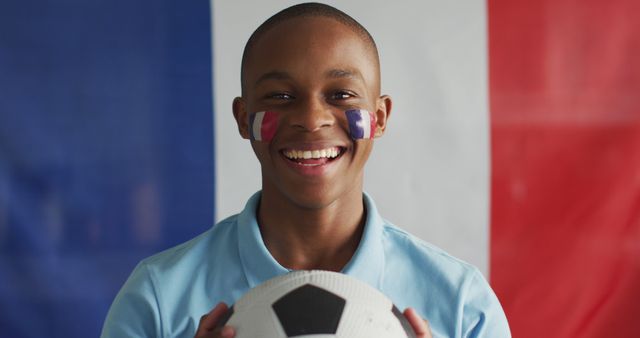 Image of happy african american boy with flag of france holding soccer ball. Cheering, sport, soccer fan and patriotism concept.