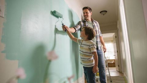 Father Teaching Son Painting Teal Hallway Wall With Roller During Home Renovation
