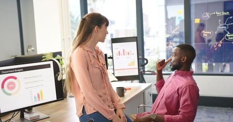 Diverse Colleagues Analyzing Data on Computer Screens in Modern Office