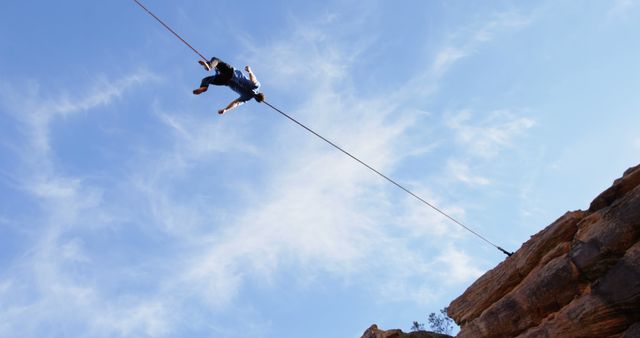 Adventurous Person Ziplining Over Mountain Cliffs with Clear Blue Sky - Download Free Stock Images Pikwizard.com