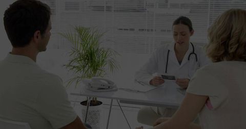 Physician consulting couple on medical report in clinical office