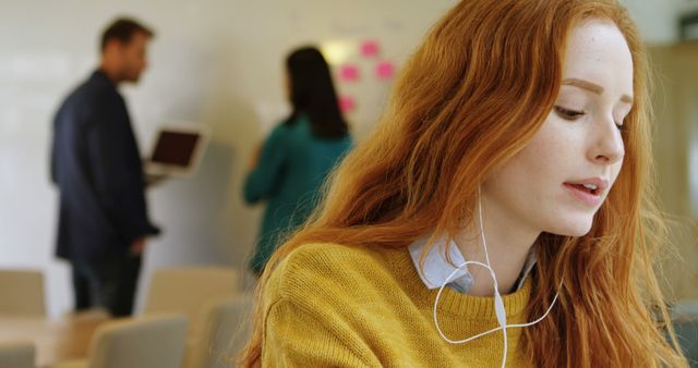 Young woman with red hair working in modern office space - Download Free Stock Images Pikwizard.com