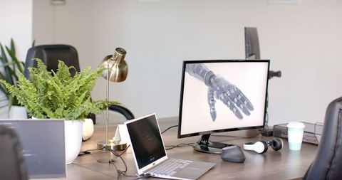 Robotic hand displayed on computer in modern office workspace