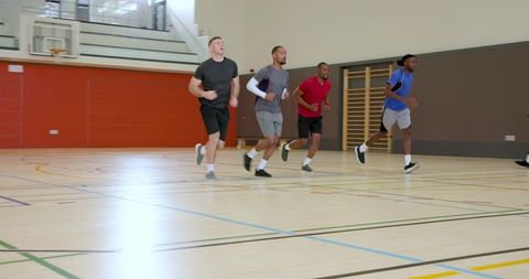 Male athletes sprinting across indoor basketball court during high-energy team training