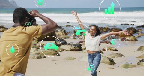 Couple on beach, man shooting woman running, laughing with green sustainability overlays