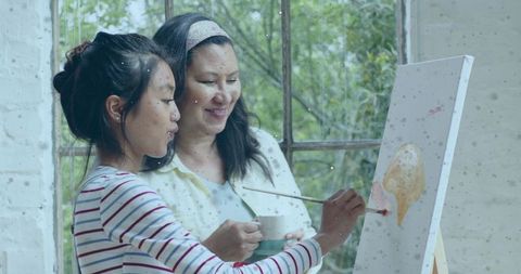 Mother and daughter painting together by window sharing creative mentorship and bonding