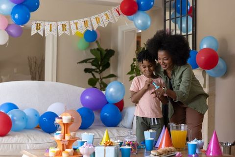 African american mother and son celebrating birthday with colorful balloons and cupcakes