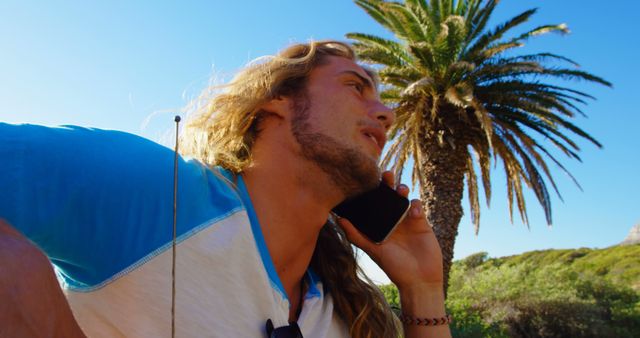 Young Man with Long Hair Making Phone Call Outdoors on Sunny Day - Download Free Stock Images Pikwizard.com