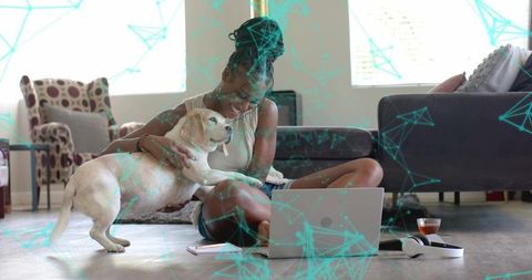 Woman Enjoying Time with Dog Next to Laptop and Tea in Cozy Living Room