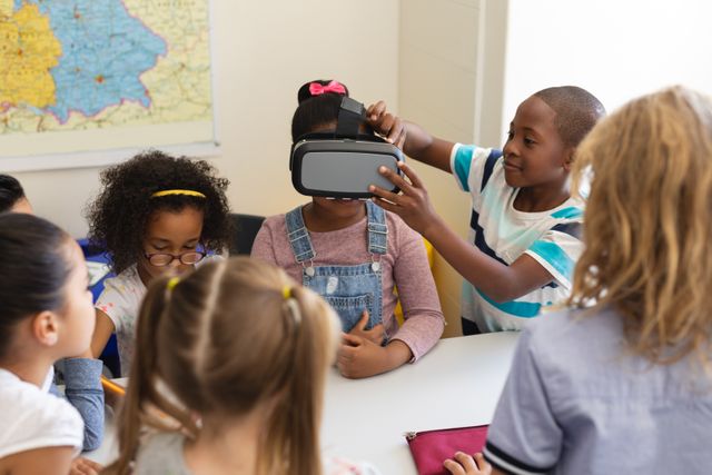 Front view schoolkids using virtual reality headset one of them help his classmate to put it on her head in classroom of elementary school