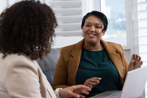 African american colleagues having one-on-one business conversation on couch with laptop