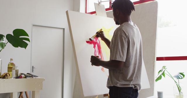 African american male artist painting on canvas at art studio. art, hobby and creative occupation concept