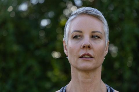 Contemplative mature woman with short silver hair looking left against soft green bokeh
