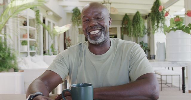 Smiling Man Relaxing with Coffee in Greenhouse Patio - Download Free Stock Images Pikwizard.com