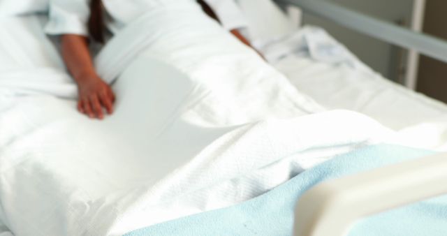 Person is lying in a hospital bed with white sheets, suggesting medical care and recovery. Suitable for healthcare, medical, and hospital-themed uses such as brochures, websites, and educational materials about patient care, hospital stays, and medical treatments.