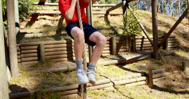 A young boy enjoys a playful moment on a swing in a park, with copy space. His motion is captured mid-swing, conveying a sense of carefree childhood joy.