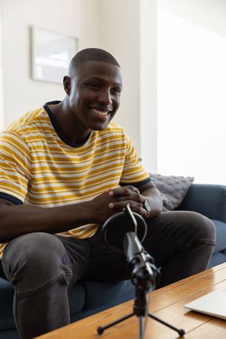 Man recording podcast at home in cozy living room setting