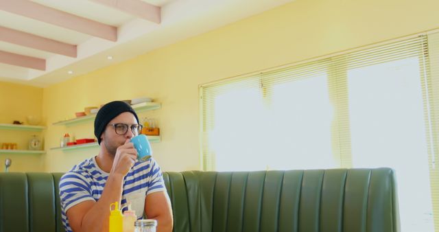 Man in Cafeteria Wearing Beanie and Striped Shirt Drinking Coffee - Download Free Stock Images Pikwizard.com