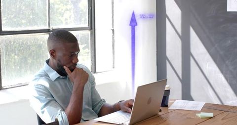 Focused Professional Analyzing Laptop Data Near Sunlit Office Window