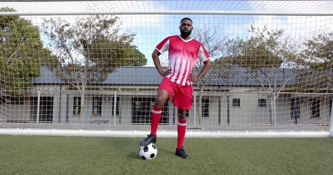 Confident Soccer Player in Red Uniform with Ball on Turf Field