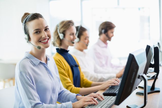 Customer service team working in a call center, wearing headsets and using computers. Ideal for illustrating concepts related to customer support, business communication, teamwork, and professional work environments. Suitable for use in business presentations, websites, and marketing materials focused on customer service and support.