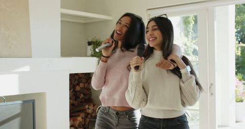 Diverse women enjoy karaoke at home singing together