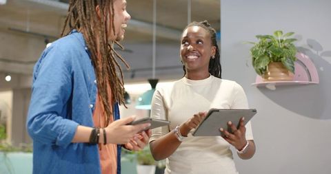 African American coworkers collaborating with tablet in modern office space