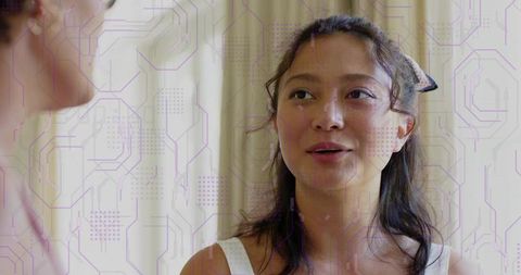 Chinese woman talking in intimate interior with cream curtains and purple tech overlay