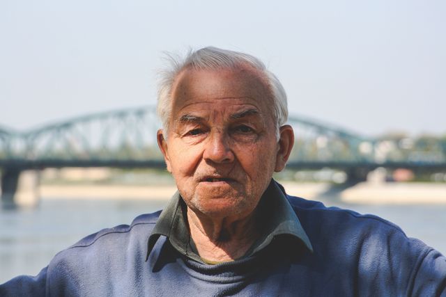 Elderly man standing near a riverside on a sunny day - Download Free Stock Photos Pikwizard.com